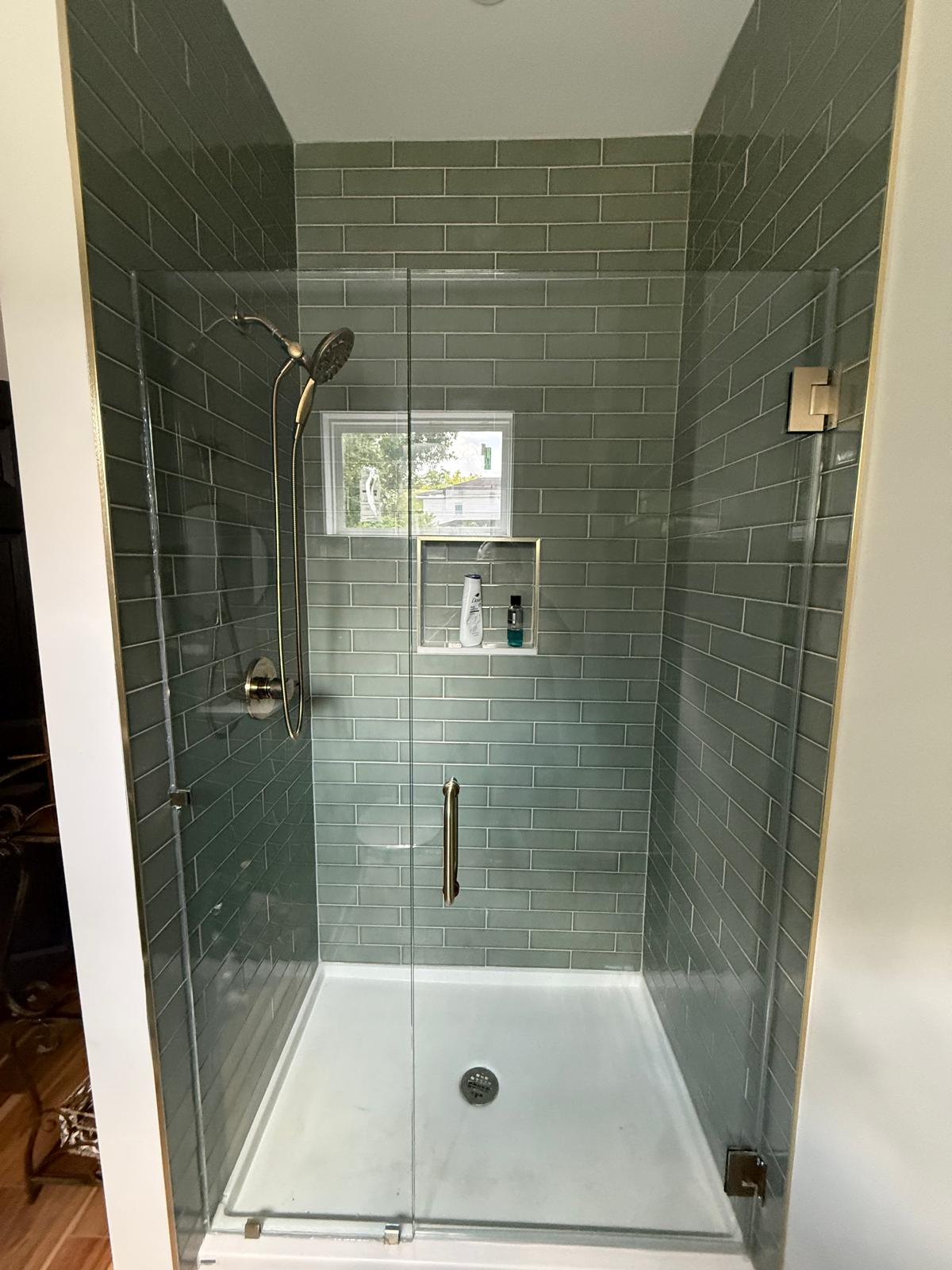 Clear glass shower enclosure with dark tile