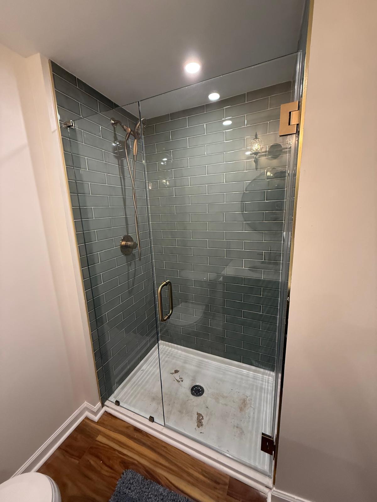 Corner glass shower enclosure with gray tile