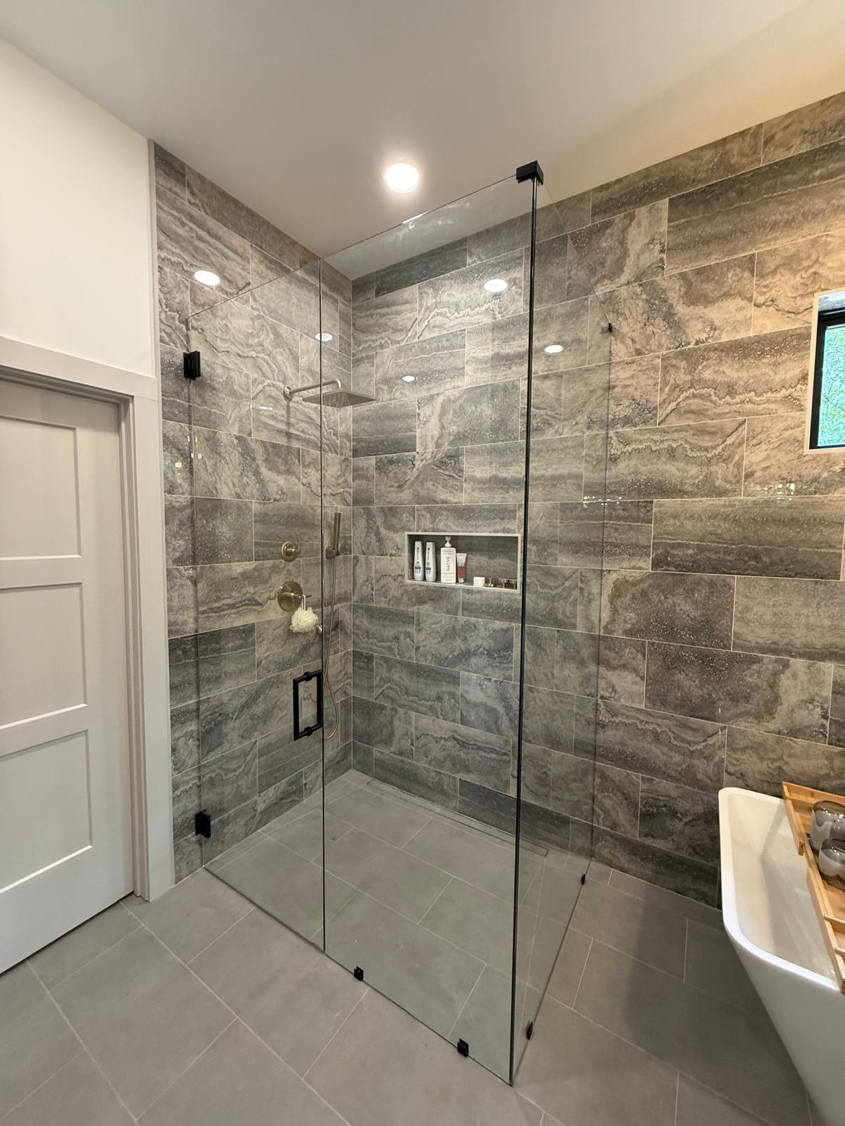Frameless shower door and fixed panel with gray stone tile
