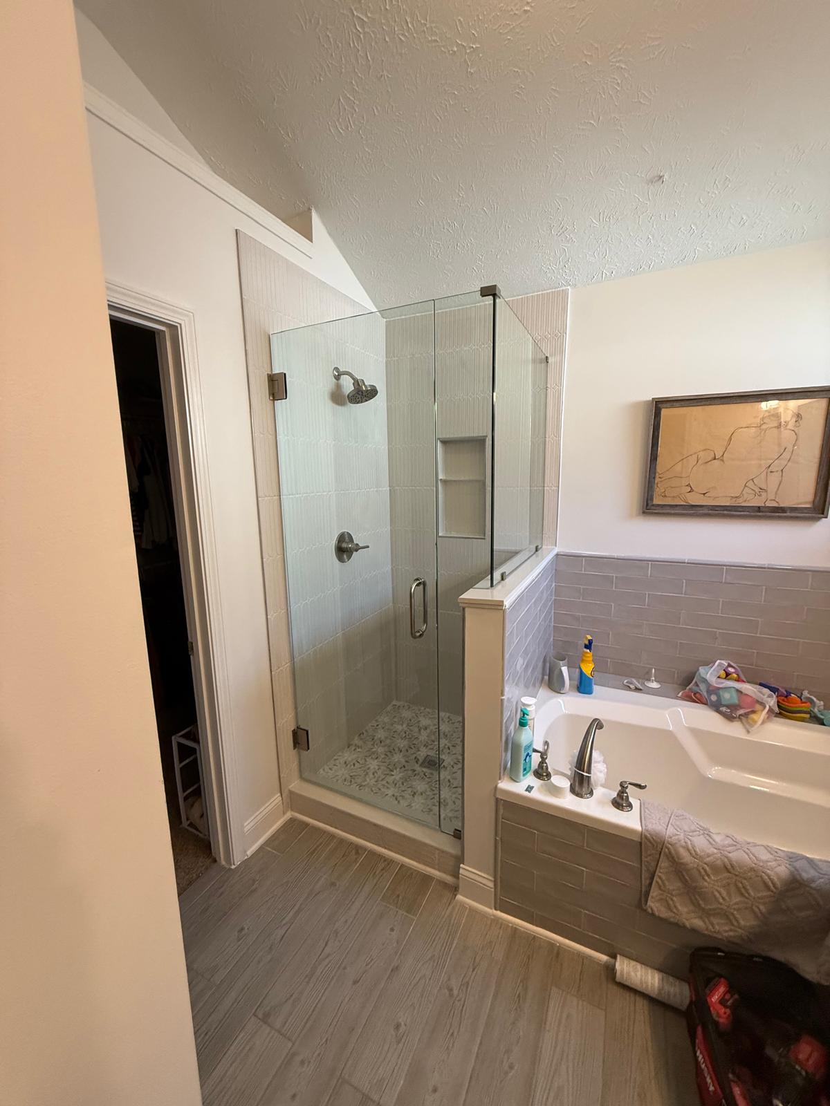 Glass shower enclosure beside a soaking tub in a remodeled bathroom