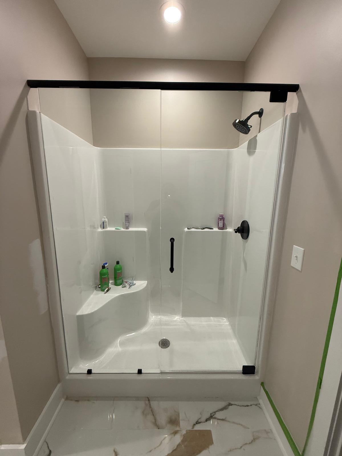 Glass shower door with header bar on a one-piece shower unit