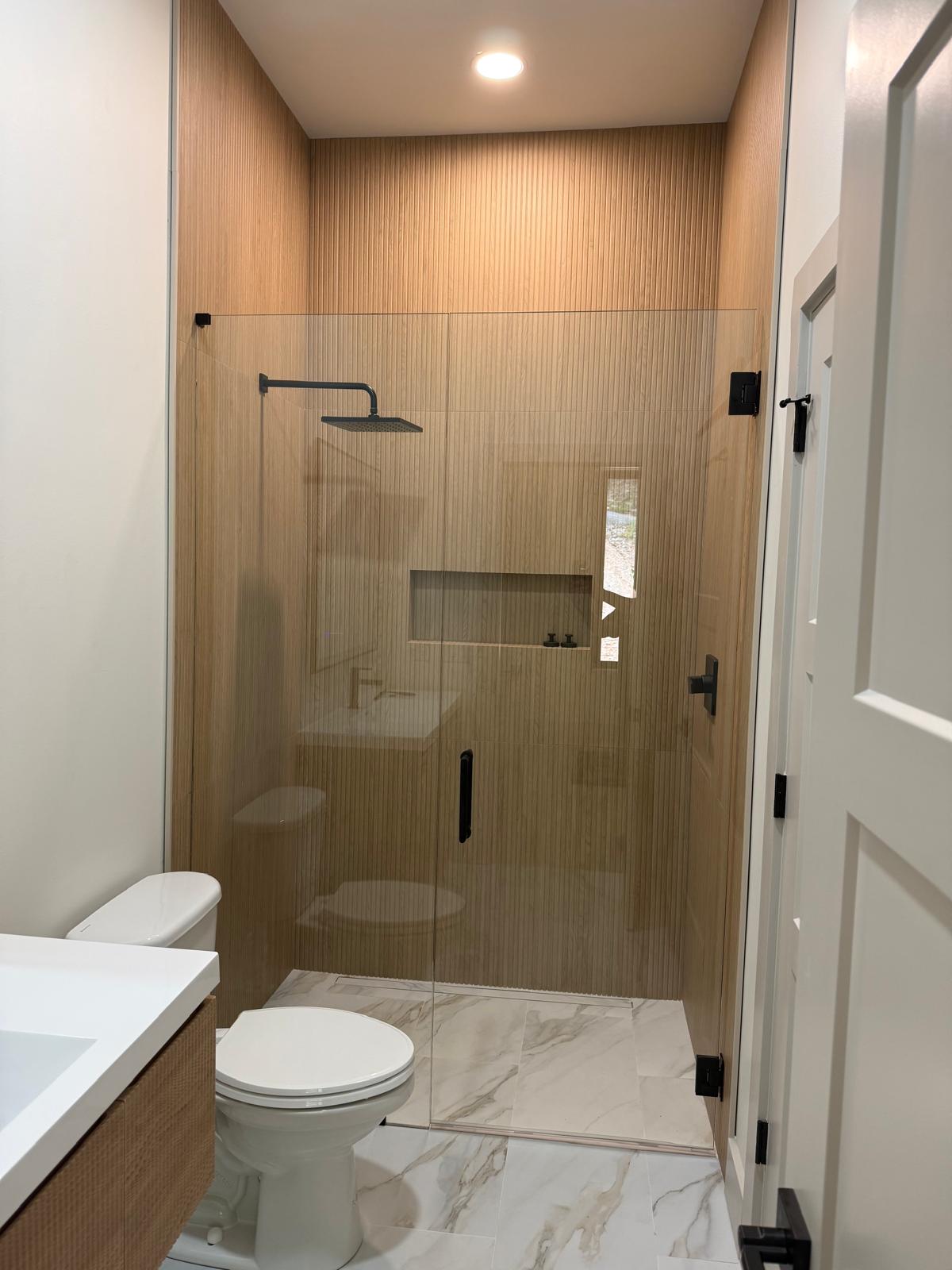 Glass shower enclosure with tan tile
