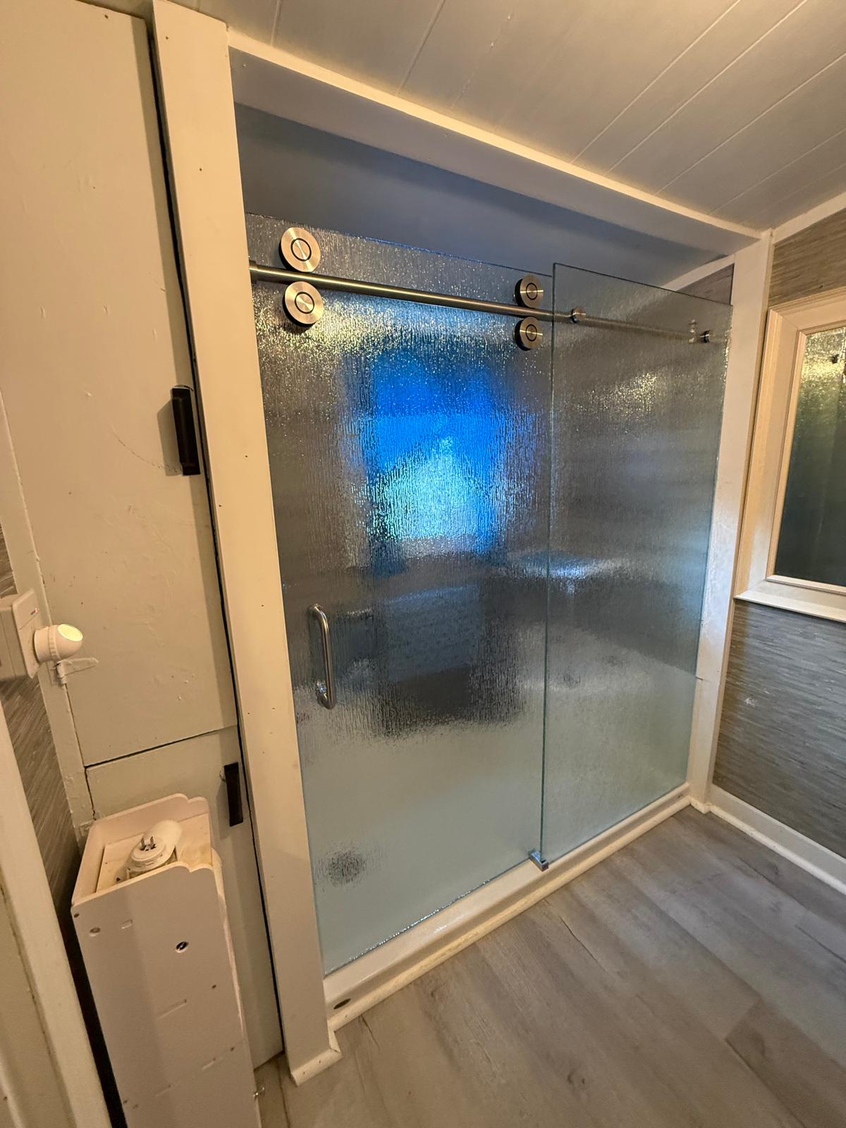 Sliding glass shower door with blue tile