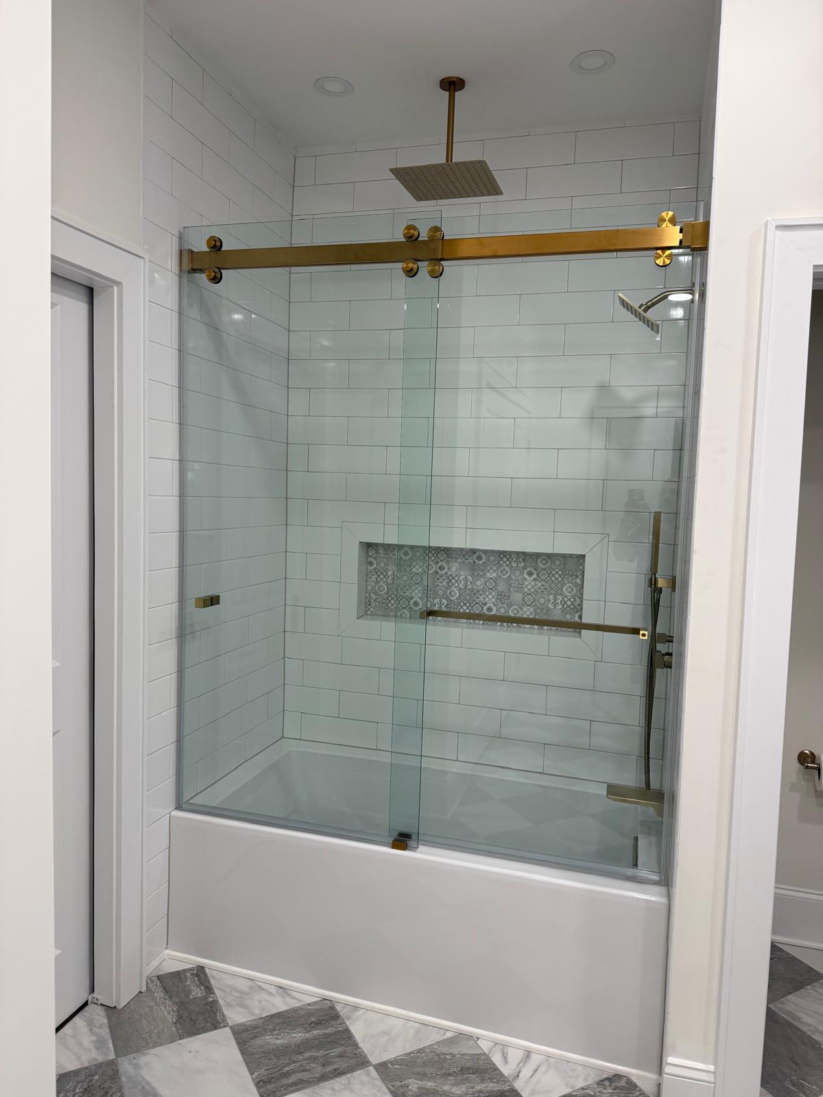 Sliding glass tub door with brushed gold roller hardware